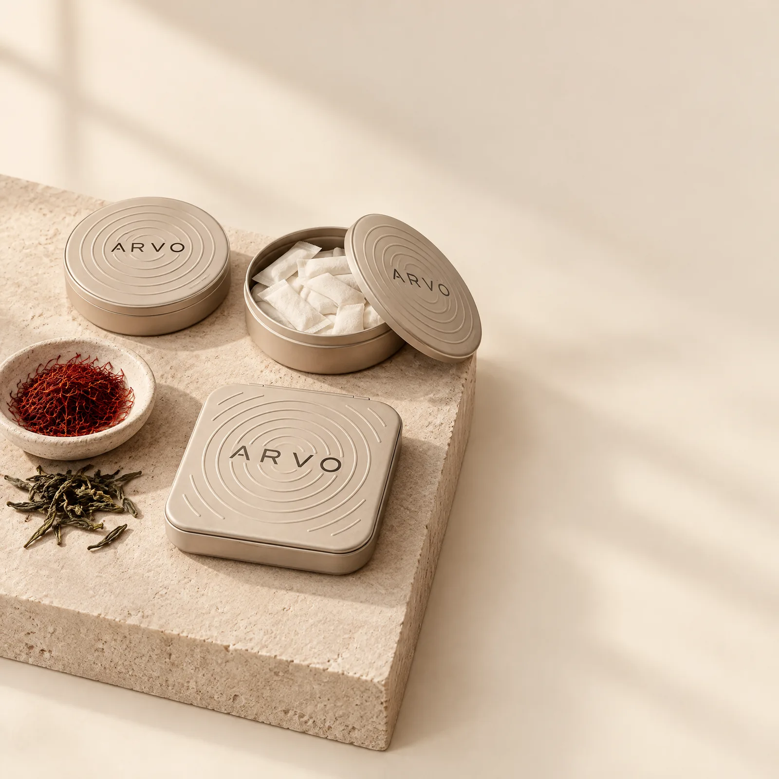 ARVO cans and the ripple metal box on a stone plinth with saffron threads and tea leaves
